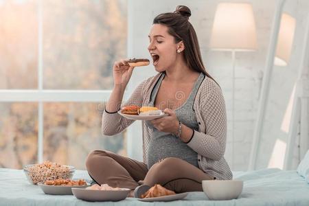 饥饿的怀孕的女性的人尖锐刺人的美味的炸面圈照片