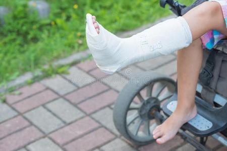 精心选择的focu一个小男孩坐在椅子上, 胳膊断了, 在石膏上.