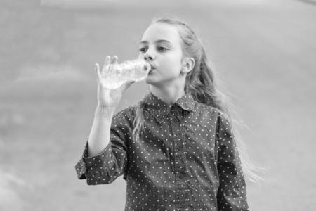 口渴的小孩喝饮料新鲜的水从塑料制品英语字母表的第2个字母照片