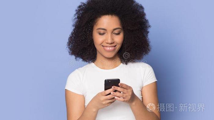 微笑的非洲的美国人女孩使用现代的蜂窝式便携无线电话发短信