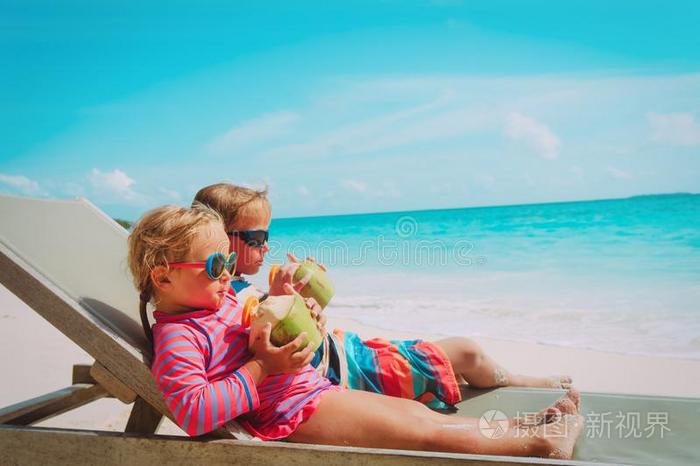 小的男孩和女孩喝饮料椰子向海滩vacati向