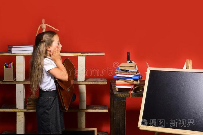 女孩看台在近处黑板,复制品空间.小孩和学校日用品