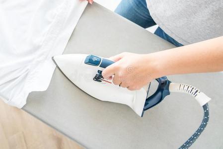 顶看法关于女性的手熨烫白色的衬衫向熨烫板照片