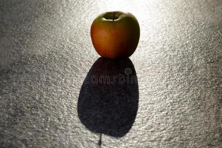 特写镜头射手关于红色的苹果和阴影向灰色的表面-完美的照片