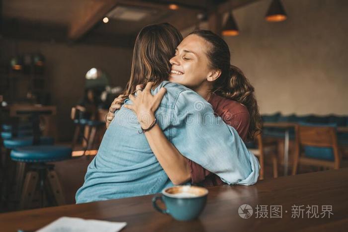 幸福的年幼的女人热烈地拥抱她最好的朋友,一次采用一c一fe