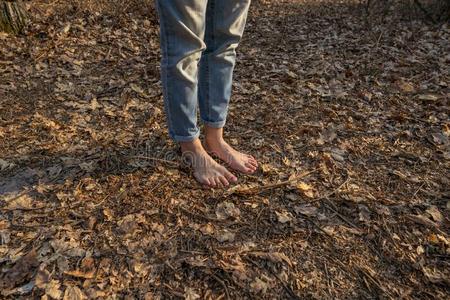 赤脚的沉淀物向森林地面.无鞋的人照片