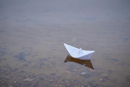 折纸手工纸小船不固定的向指已提到的人表面关于蓝色水.纸照片
