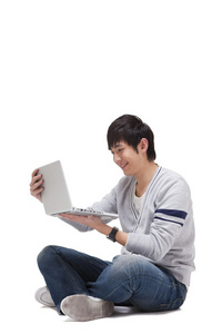 年轻男人坐在地上使用笔记本电脑照片