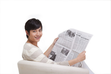 年轻男人坐在沙发上看报纸照片