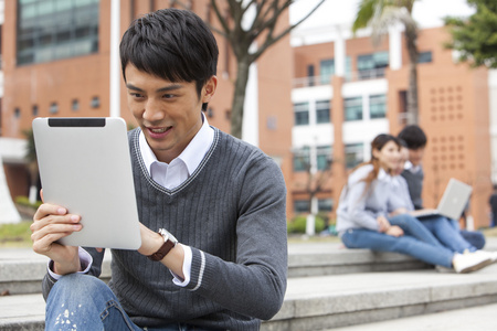 大学操场年轻大学生在校园里使用平板电脑照片