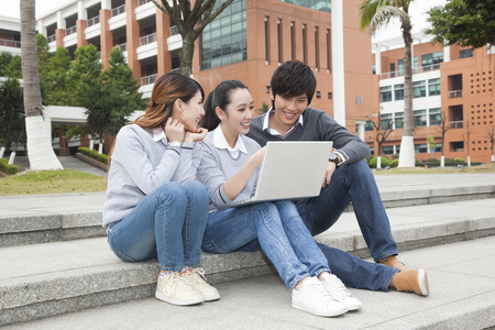 湖畔大学年轻大学生在校园里使用笔记本电脑照片