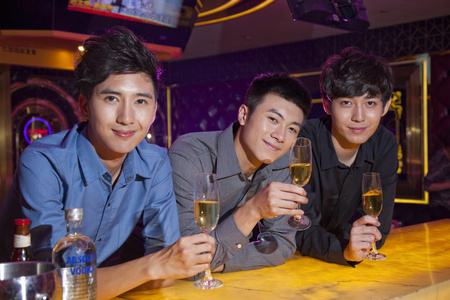 ktv聚会酒吧柜台上的帅哥男子在酒吧使用数码平板电脑一群年轻人在ktv