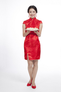 棚拍节日身穿红色旗袍的年轻女人端着饺子