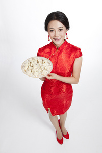 棚拍节日身穿红色旗袍的年轻女人端着饺子