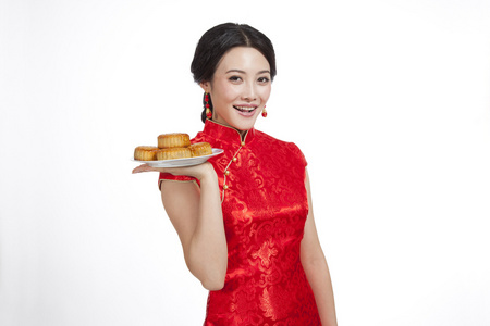 棚拍节日身穿红色旗袍的年轻女人端着月饼照片