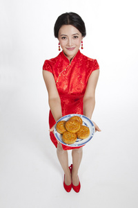 棚拍节日身穿红色旗袍的年轻女人端着月饼照片