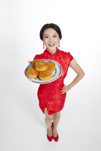 棚拍节日身穿红色旗袍的年轻女人端着月饼照片