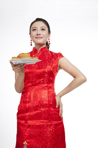 棚拍节日身穿红色旗袍的年轻女人端着月饼