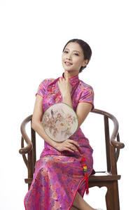 棚拍身穿旗袍的年轻女人坐在中式椅上拿着团扇