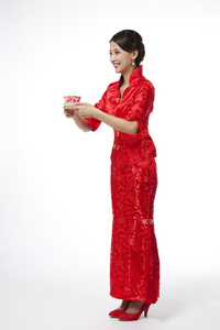 棚拍节日身穿红色旗袍的年轻女人端茶杯