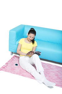 棚拍年轻女人坐在地毯上听音乐看杂志