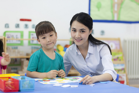 幼儿园女老师辅导儿童做手工