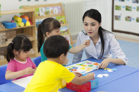 幼儿园女老师辅导儿童做手工