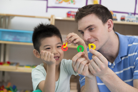幼儿园外教男老师和儿童一起玩字母游戏