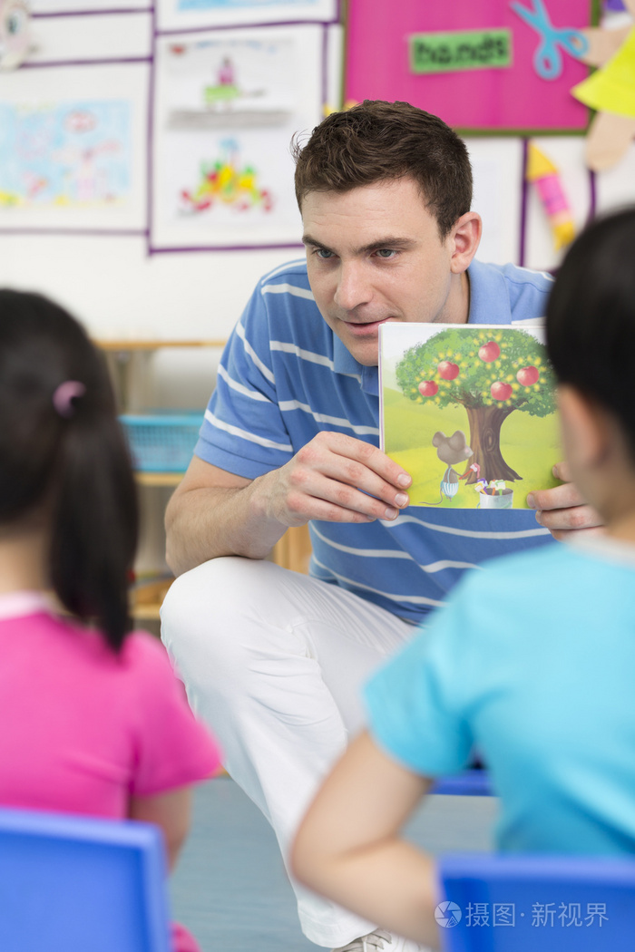 幼儿园外教男老师和儿童一起看画册