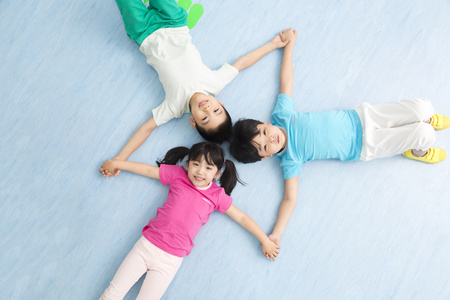 幼儿园儿童躺在地板上手拉手微笑照片