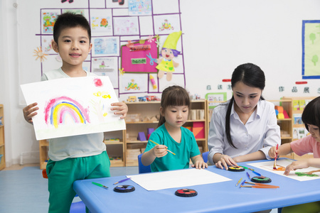 幼儿园女老师和儿童展示绘画作品