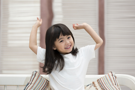 伸懒腰姑娘快乐的小女孩坐在沙发上照片