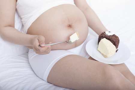 孕妇坐在床上吃蛋糕