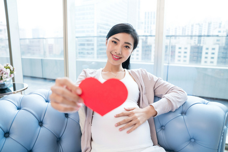 年轻孕妇坐在沙发上多文化的朋友和怀孕妇女在婴孩党乐趣年轻孕妇孕妇