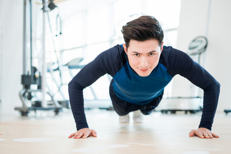 平板支撑年轻男子做俯卧撑照片