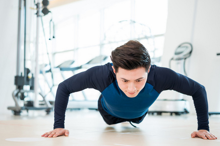 平板支撑年轻男子做俯卧撑照片
