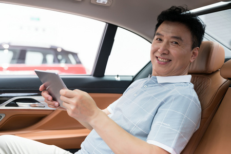 商务男士坐在车里使用平板电脑照片