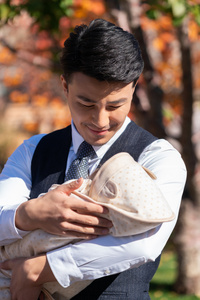 年轻的爸爸抱着婴儿照片