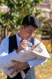 年轻的爸爸抱着婴儿照片