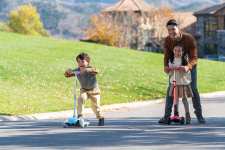 里牵着父母的手快乐的孩子爸爸带着孩子在玩滑板车一家人在家里吃晚饭