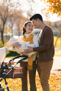 年轻夫妻推着婴儿车散步