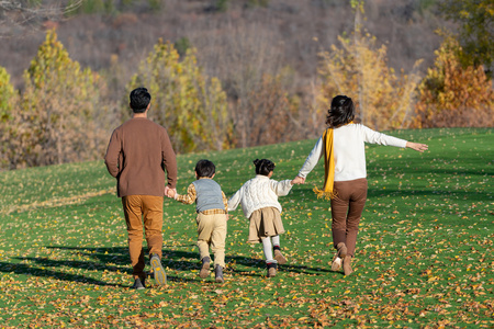 年轻夫妻带着孩子在公园玩耍照片