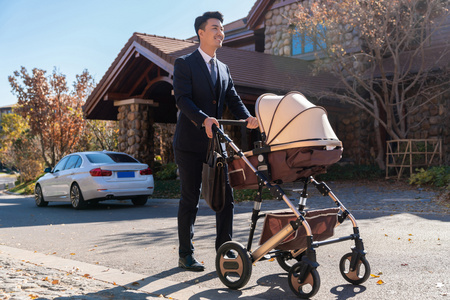 年轻的父亲与公园双推车婴儿车年轻夫妻推着婴儿车散步年轻夫妻推着