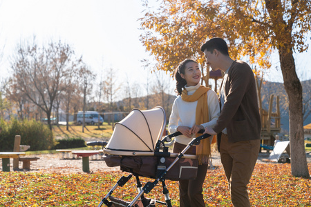 年轻夫妻推着婴儿车散步