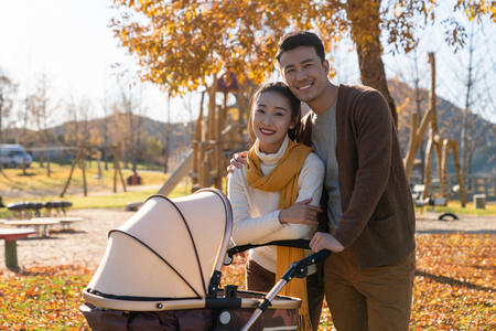 年轻夫妻推着婴儿车散步