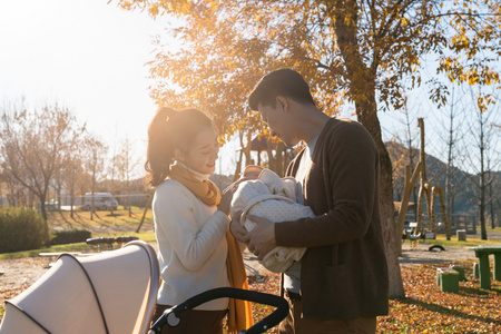 年轻夫妻推着婴儿车散步