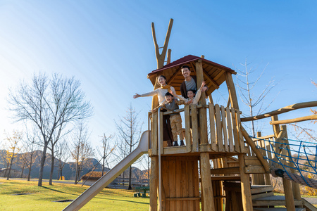 亲子滑梯年轻夫妻带着孩子在公园玩耍照片