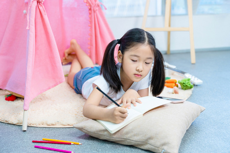 小女孩趴在地板上写作业照片