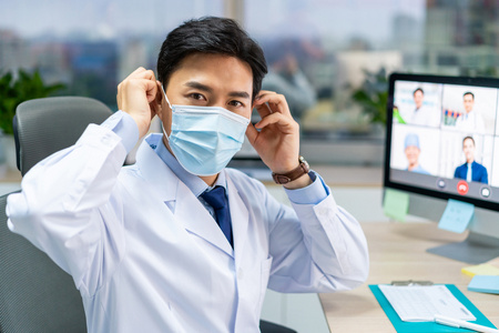 年轻医生戴着口罩在办公室工作照片
