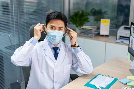 年轻医生戴着口罩在办公室工作照片